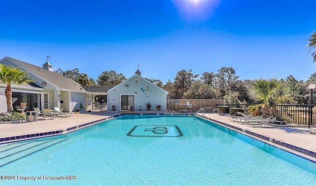 community pool with a patio and fence