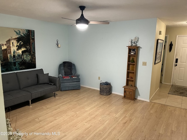 living room with light wood-style floors, baseboards, and a ceiling fan