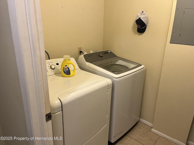 laundry room featuring washer and clothes dryer, light tile patterned flooring, laundry area, electric panel, and baseboards