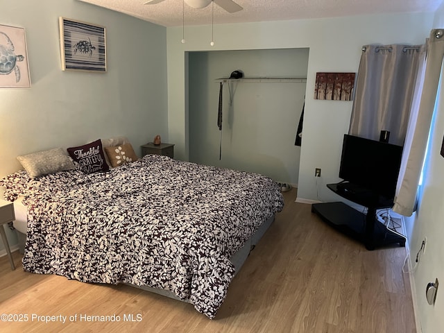 bedroom with a closet, ceiling fan, a textured ceiling, and wood finished floors