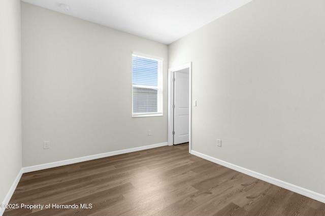 spare room featuring wood finished floors and baseboards