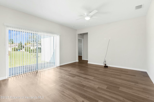 spare room featuring a ceiling fan, dark wood-style flooring, visible vents, and baseboards