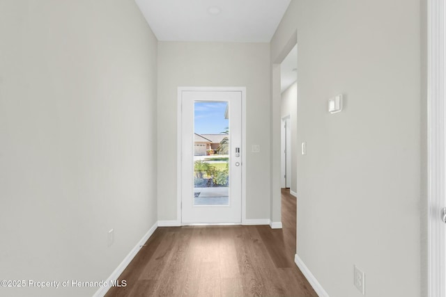 doorway to outside featuring dark wood-style flooring and baseboards