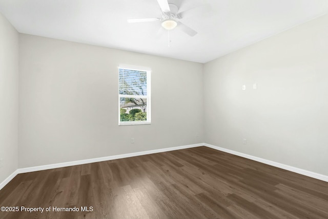 unfurnished room featuring dark wood-style floors, ceiling fan, and baseboards