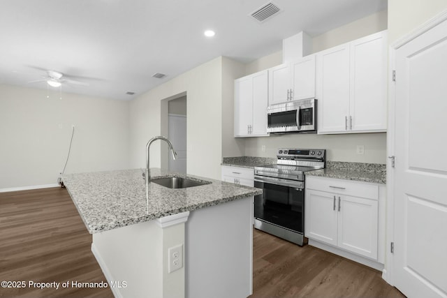 kitchen featuring appliances with stainless steel finishes, white cabinetry, a sink, and a center island with sink