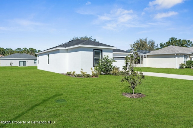 view of front facade featuring an attached garage, a front lawn, concrete driveway, and stucco siding