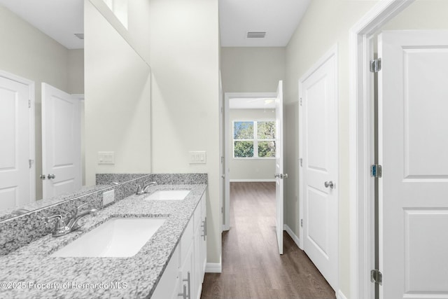 bathroom with visible vents, a sink, baseboards, and wood finished floors