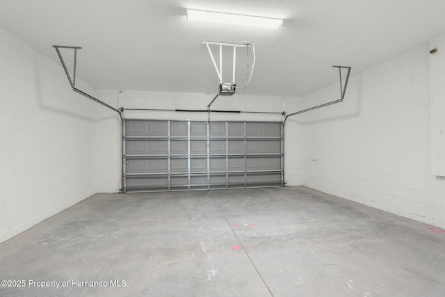 garage with a garage door opener and concrete block wall