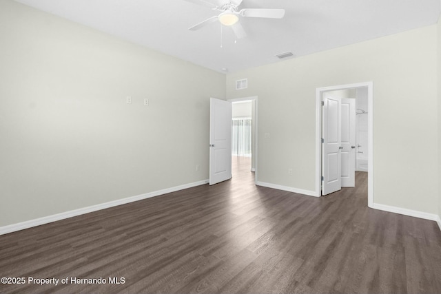 unfurnished bedroom featuring dark wood-style floors, a walk in closet, visible vents, and baseboards