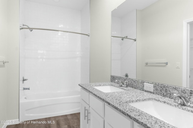 full bath featuring double vanity, a sink, bathing tub / shower combination, and wood finished floors