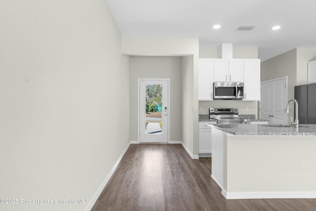 kitchen featuring light stone countertops, white cabinetry, appliances with stainless steel finishes, and a sink