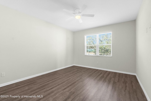 unfurnished room with baseboards, dark wood finished floors, and a ceiling fan