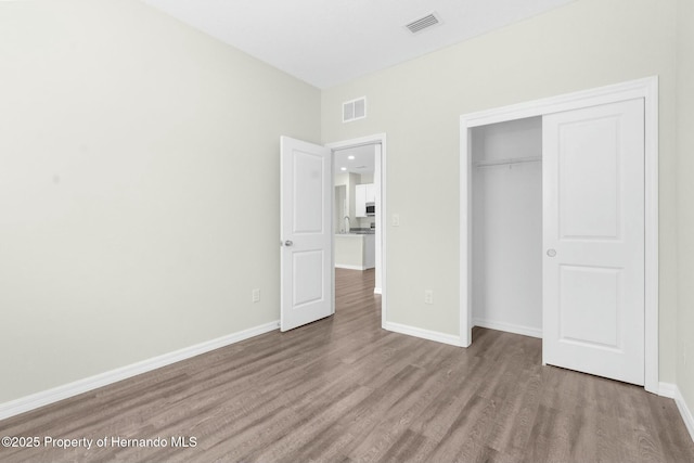 unfurnished bedroom featuring light wood finished floors, baseboards, and visible vents