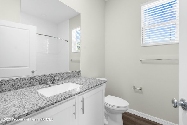 full bath featuring toilet, vanity, wood finished floors, baseboards, and walk in shower