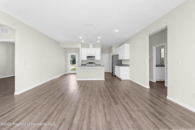 unfurnished living room featuring recessed lighting, visible vents, baseboards, and wood finished floors