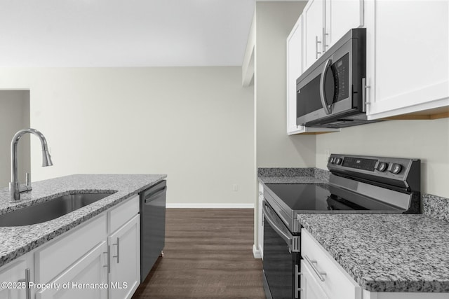 kitchen with light stone counters, dark wood-type flooring, a sink, white cabinets, and appliances with stainless steel finishes