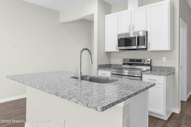 kitchen featuring stainless steel appliances, white cabinets, a center island with sink, and a sink