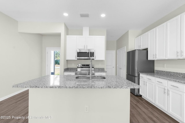 kitchen with stainless steel appliances, visible vents, white cabinetry, an island with sink, and light stone countertops