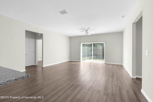 unfurnished living room with dark wood-type flooring, a ceiling fan, visible vents, and baseboards