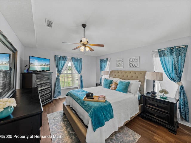 bedroom featuring ceiling fan, visible vents, and dark wood-style flooring