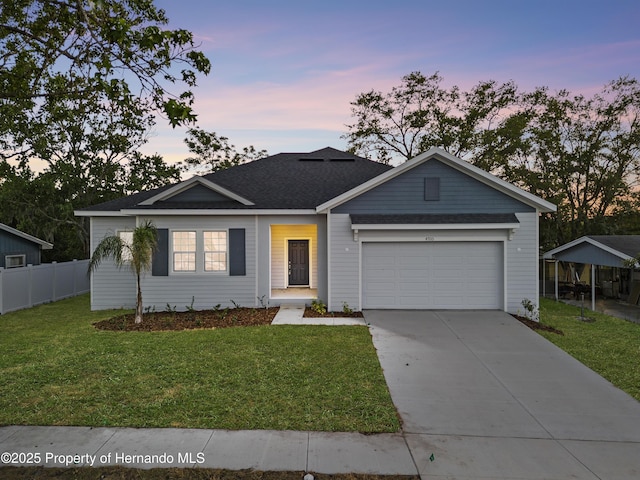 ranch-style house featuring a shingled roof, concrete driveway, a lawn, fence, and a garage