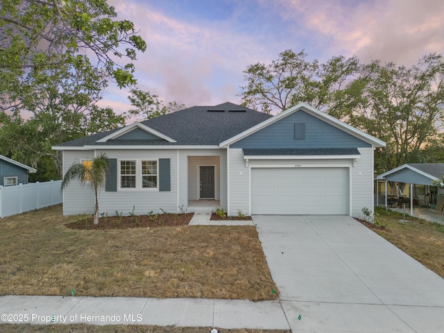 ranch-style house featuring a garage, a shingled roof, concrete driveway, fence, and a front yard