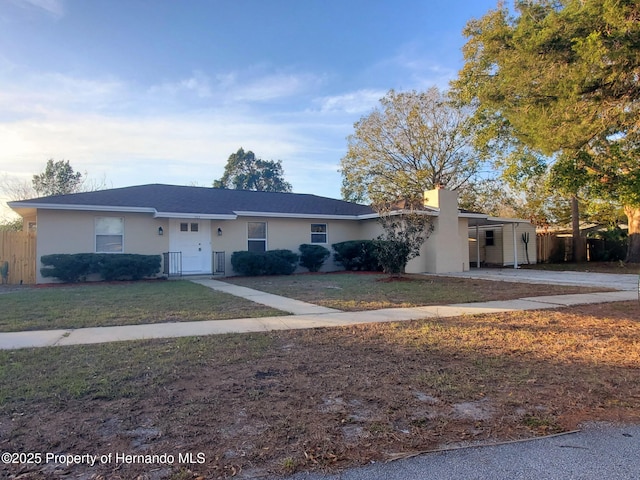 ranch-style home with a front yard, fence, and stucco siding