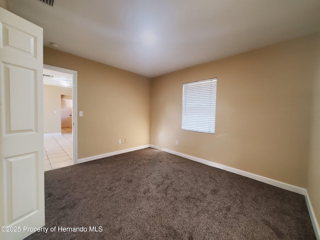 empty room featuring light carpet, baseboards, and light tile patterned floors