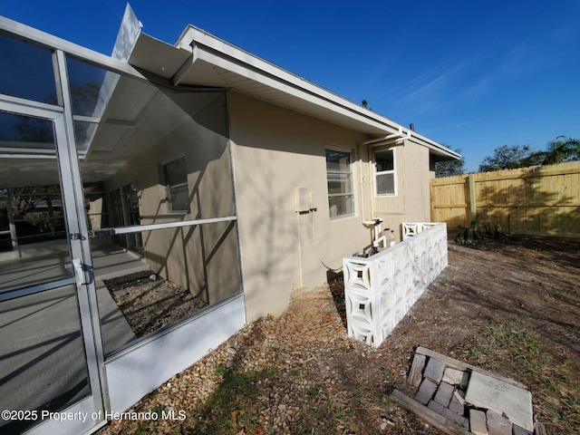 view of side of property featuring fence and stucco siding