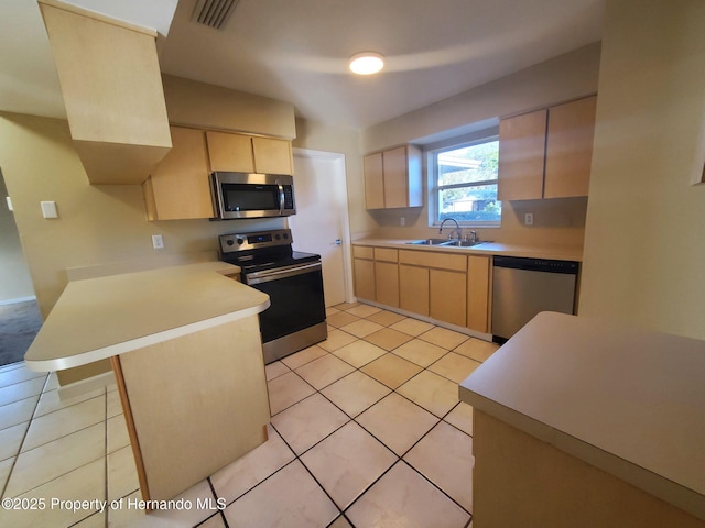 kitchen featuring stainless steel appliances, visible vents, light brown cabinetry, a sink, and a peninsula