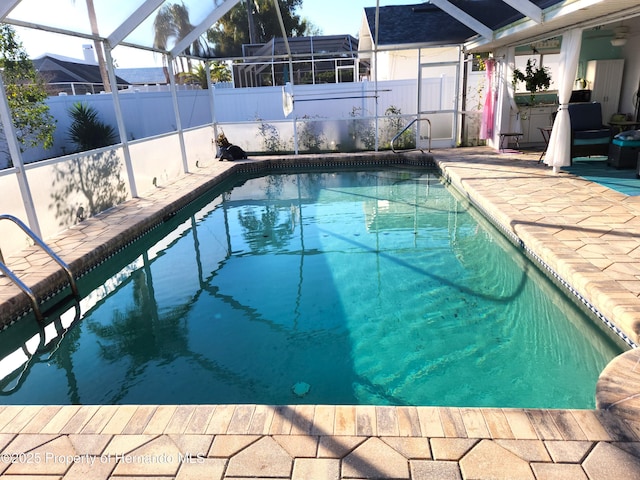 view of swimming pool featuring glass enclosure, a patio area, a fenced backyard, and a fenced in pool