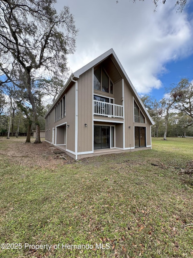 back of house with a yard and a balcony