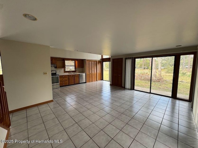 unfurnished living room with light tile patterned floors, baseboards, and a sink