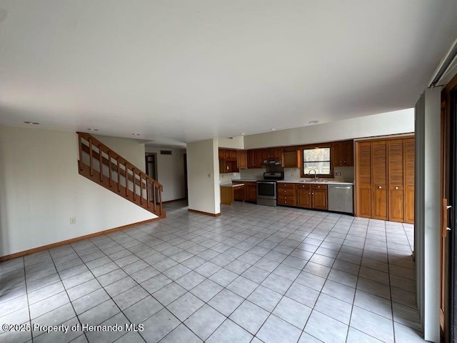 kitchen featuring baseboards, brown cabinets, stainless steel appliances, light countertops, and a sink