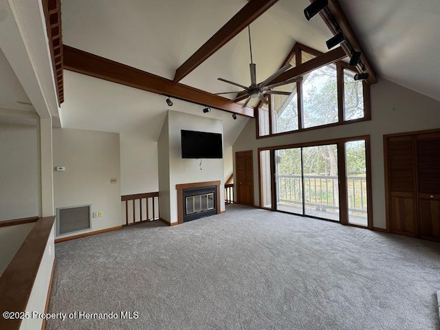 unfurnished living room with high vaulted ceiling, a glass covered fireplace, beam ceiling, and visible vents