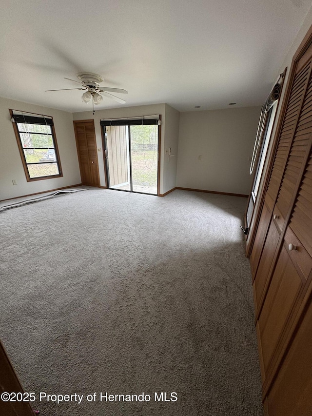 spare room with light carpet, a ceiling fan, and baseboards