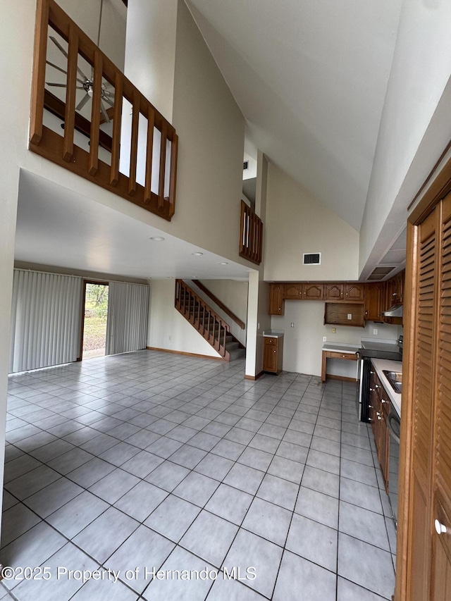 unfurnished living room with light tile patterned floors, stairway, visible vents, and high vaulted ceiling