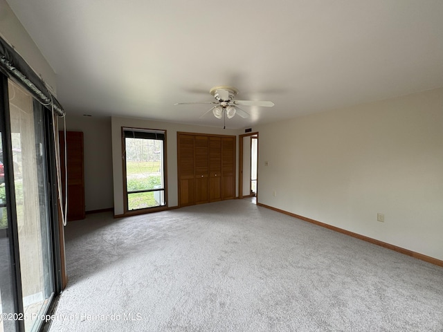 carpeted empty room with ceiling fan and baseboards