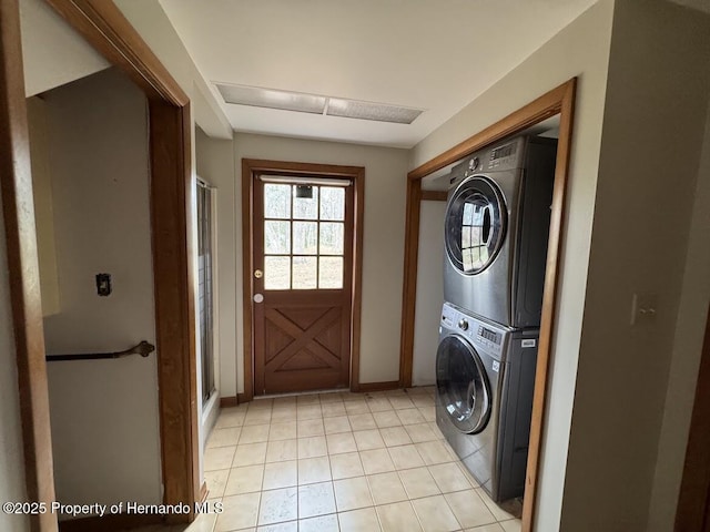 washroom with light tile patterned floors, stacked washer and dryer, laundry area, and baseboards