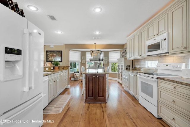 kitchen featuring visible vents, white appliances, cream cabinetry, and decorative light fixtures