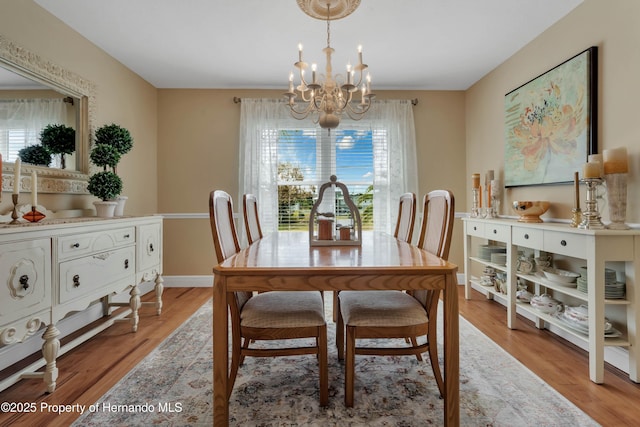 dining space with a chandelier, a wealth of natural light, light wood-style flooring, and baseboards