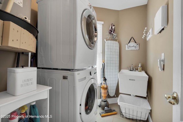 washroom featuring stacked washer and clothes dryer, a sink, and laundry area