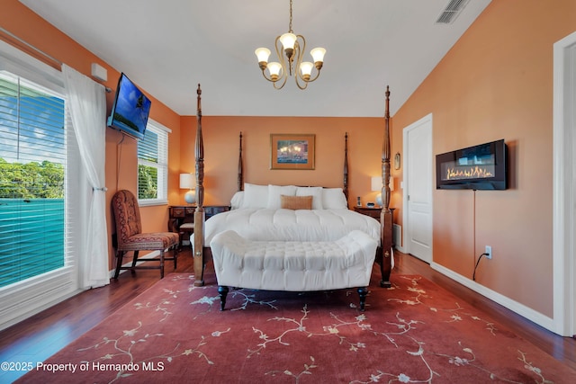 bedroom featuring baseboards, visible vents, lofted ceiling, dark wood-style floors, and a notable chandelier