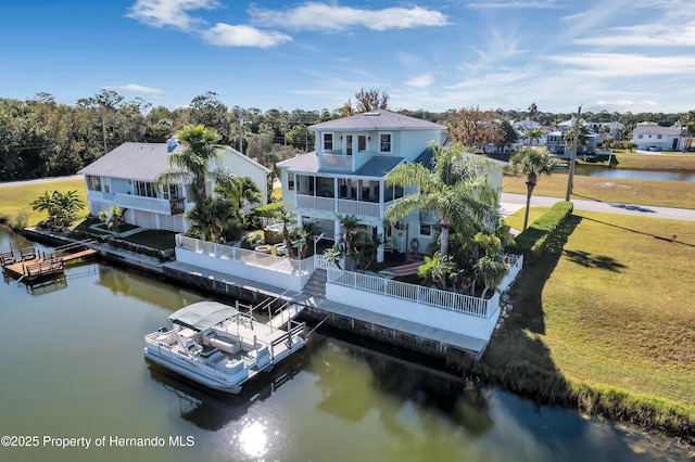 back of property with a water view, a sunroom, a residential view, and a yard