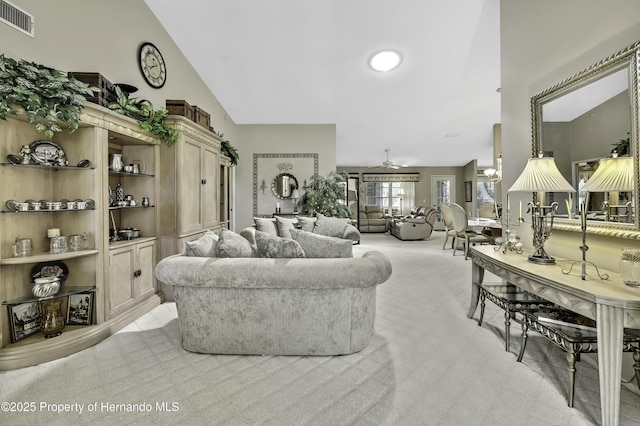 living room with high vaulted ceiling, a ceiling fan, visible vents, and light colored carpet