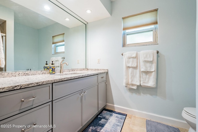 bathroom featuring baseboards, vanity, and a healthy amount of sunlight