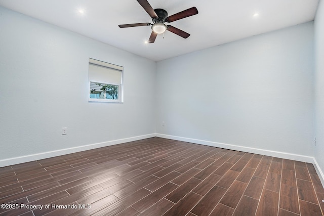 spare room with wood finish floors, a ceiling fan, and baseboards