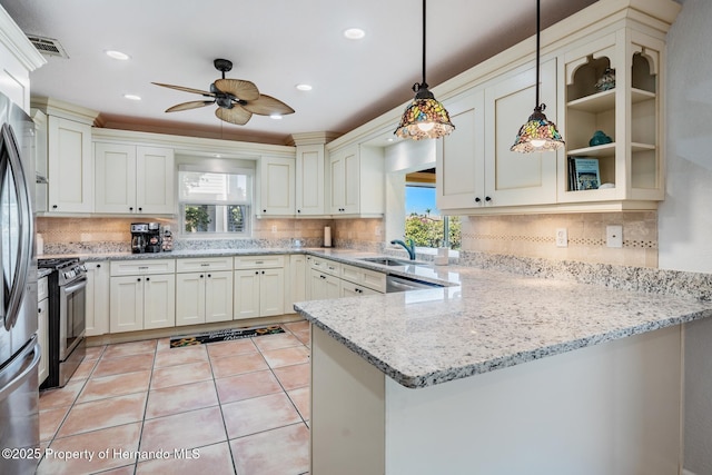 kitchen featuring decorative light fixtures, visible vents, glass insert cabinets, stainless steel gas stove, and a peninsula