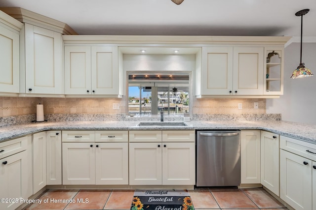 kitchen with decorative backsplash, light stone countertops, stainless steel dishwasher, a sink, and light tile patterned flooring