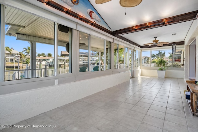 unfurnished sunroom featuring plenty of natural light, a water view, and a ceiling fan